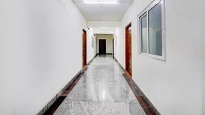 A long, narrow hallway with white walls and a polished marble floor. - Super Collection O Sathyabama University (Chennai)