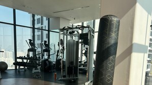 Ein Fitnessstudio mit Trainingsgeräten, großen Fenstern und Holzboden.