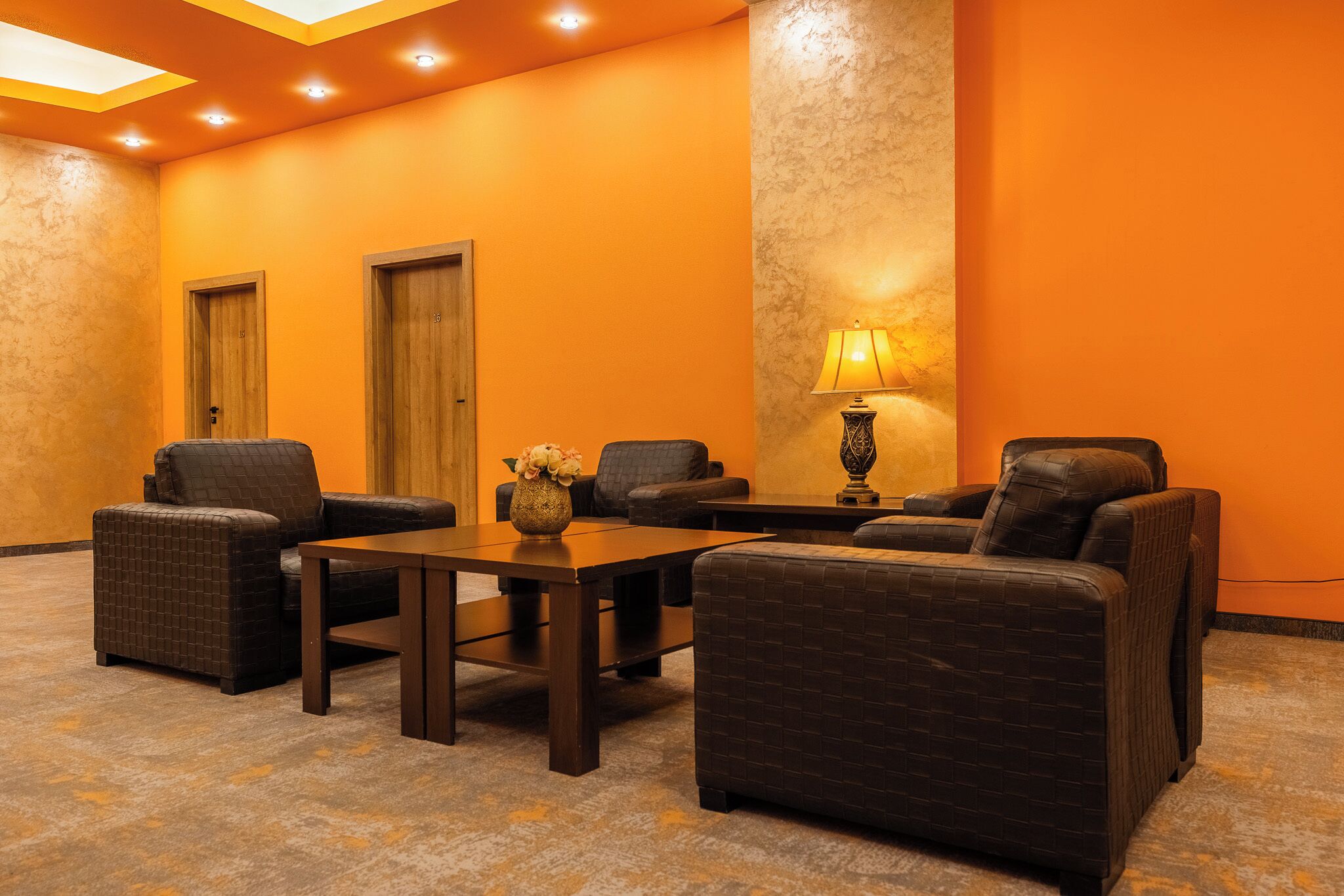 Una habitación con dos puertas de madera, una mesa y cuatro sillas tapizadas.