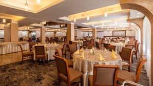 Un comedor amplio con mesas redondas, sillas e iluminación moderna.