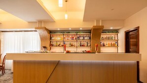 Zona de bar con mostrador de madera, estantes con botellas y un área de asientos con una silla.