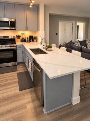 A modern kitchen with a central island, stainless steel appliances, and a grey color scheme.