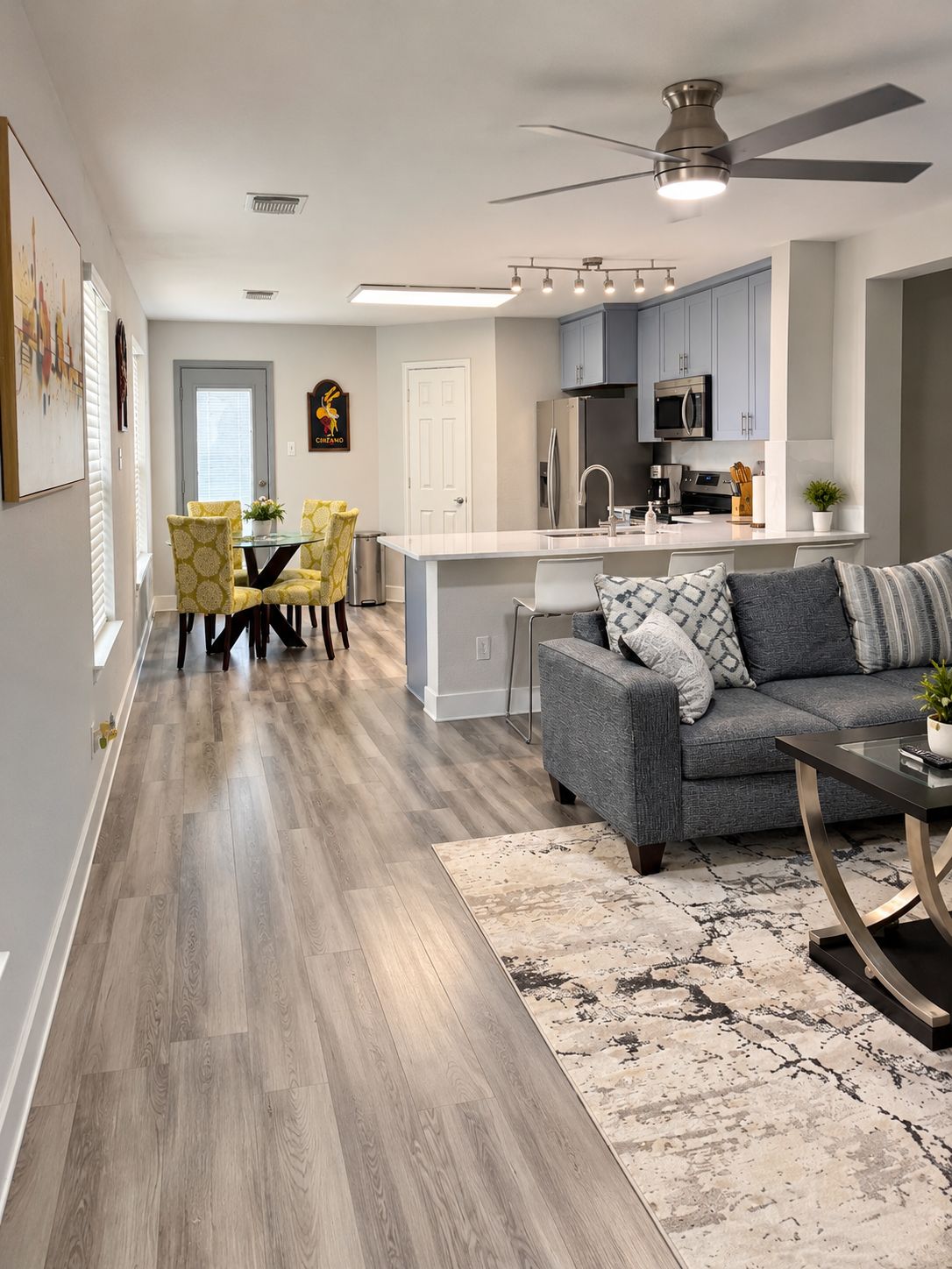 A modern kitchen with grey cabinets, a stainless steel refrigerator, and a microwave.