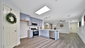 Uma cozinha moderna com armários azul claros, uma ilha central e um micro-ondas.