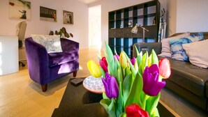 A modern living room with a purple armchair, a sofa with patterned cushions, and a coffee table with a decorative plate. - Apt w Garden Oasis in Finchley (London)