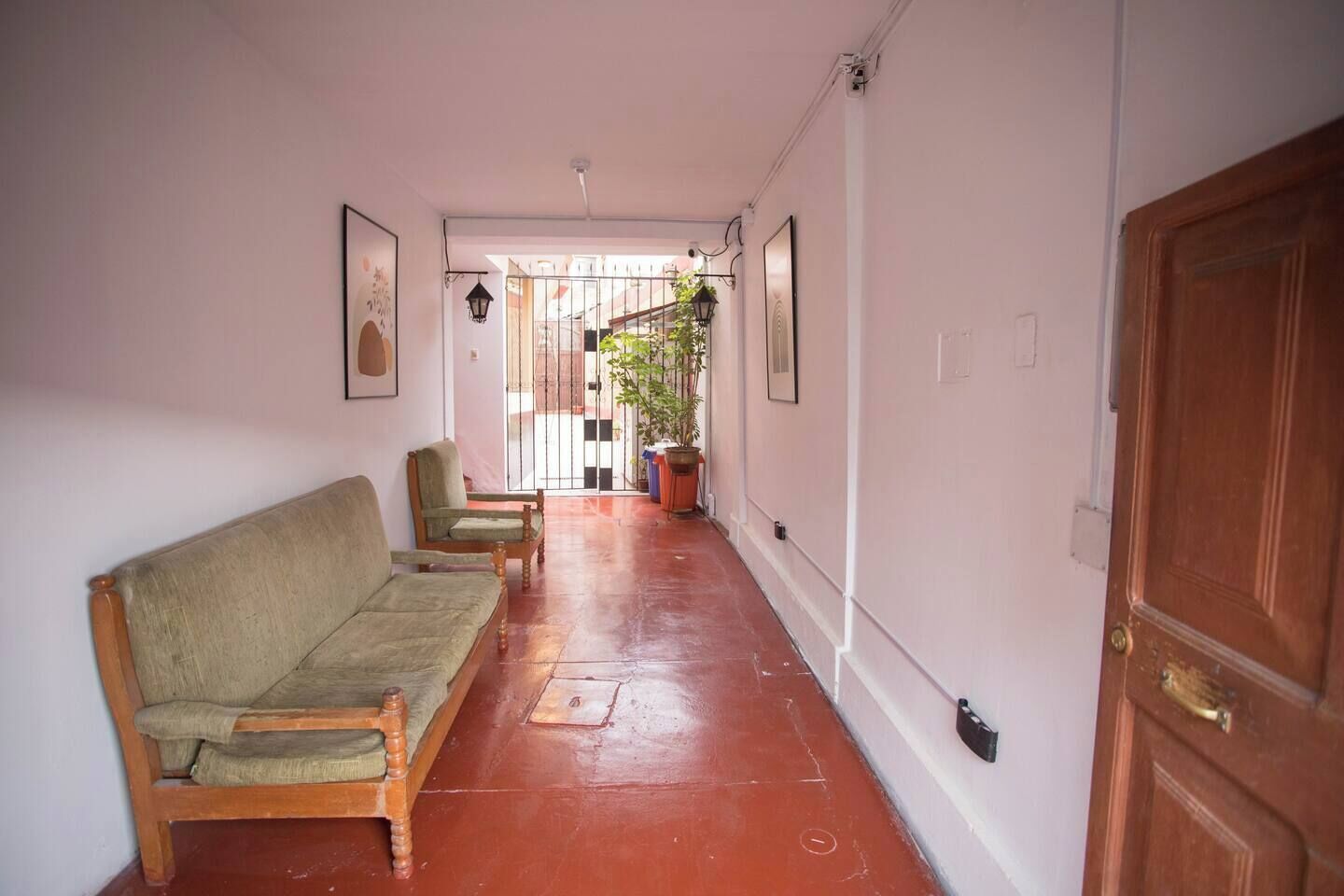 A hallway with a wooden door, a wooden bench, and a potted plant.