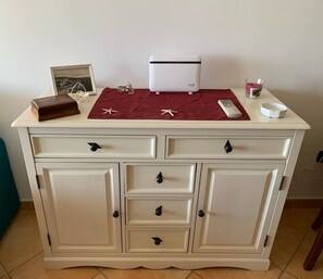 Ein weißer Schrank mit Schubladen und einem kleinen weißen Gerät darauf.