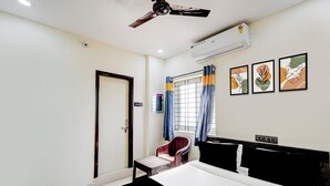 A hotel room with a bed, a chair, a desk, a ceiling fan, an air conditioning unit, and a window with curtains. - Hotel O Snist University Hyderabad (Hyderabad)