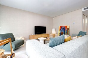 A modern hotel room with a grey sofa, a television, a painting, and a lamp. - Luxury vacation with a terrace and private pool (Marbella)