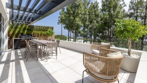 An outdoor patio with a grill, dining table, chairs, and a view of trees and buildings. - Luxury getaway with terrace and private pool (Marbella)