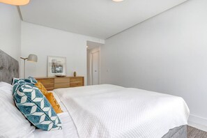 A bedroom with a bed, bedside lamp, dresser, and a door leading to another room. - Luxury vacation with a terrace and private pool (Marbella)