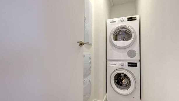 A laundry room with two stacked front-loading washing machines and a door leading to another room. - Luxury getaway with terrace and private pool (Marbella)
