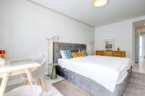 A modern bedroom with a bed, bedside table, lamp, and a desk with a chair. - Luxury vacation with a terrace and private pool (Marbella)