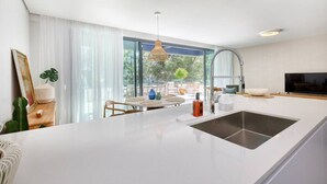 A modern kitchen with a large island, a dining area with chairs, a television, and a view of the outdoors. - Luxury getaway with terrace and private pool (Marbella)