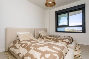 A bedroom with two beds, a large window, and a hanging light fixture. - Ipanema 2-Bedroom Apartment with a View (Mijas)