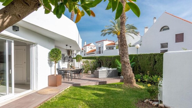 A modern house with a patio, a dining area, and a well-maintained garden. - Modern ground-floor apartment with a private garden in Nueva Andalucía (Marbella)