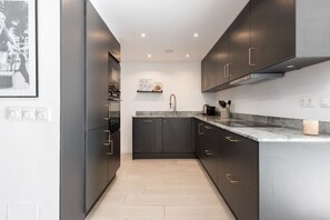 Eine moderne Küche mit dunklen Schränken, einer Granit Arbeitsplatte und einer Edelstahl-Dunstabzugshaube.