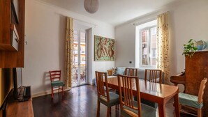 Zona pranzo con un tavolo e sedie in legno, una televisione e un quadro appeso al muro.