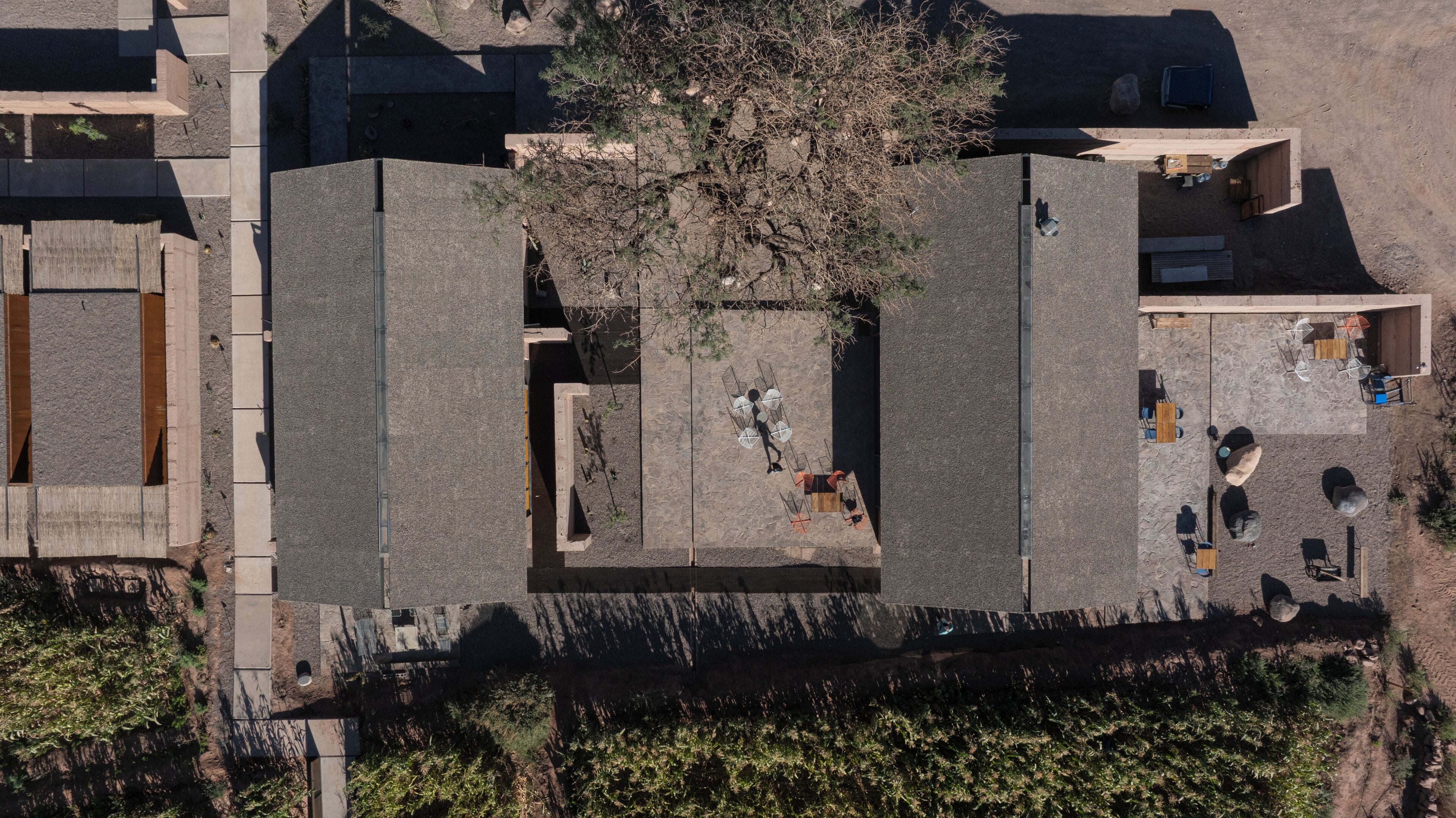 An aerial view of a courtyard with a central tree, surrounding buildings, and outdoor seating areas.