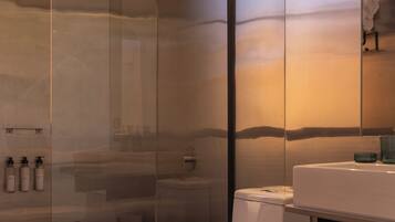 Un baño moderno con cabina de ducha de vidrio, inodoro blanco y tocador con espejo.