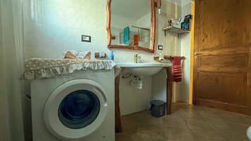 A compact bathroom with a washing machine, a sink, and a wooden door.