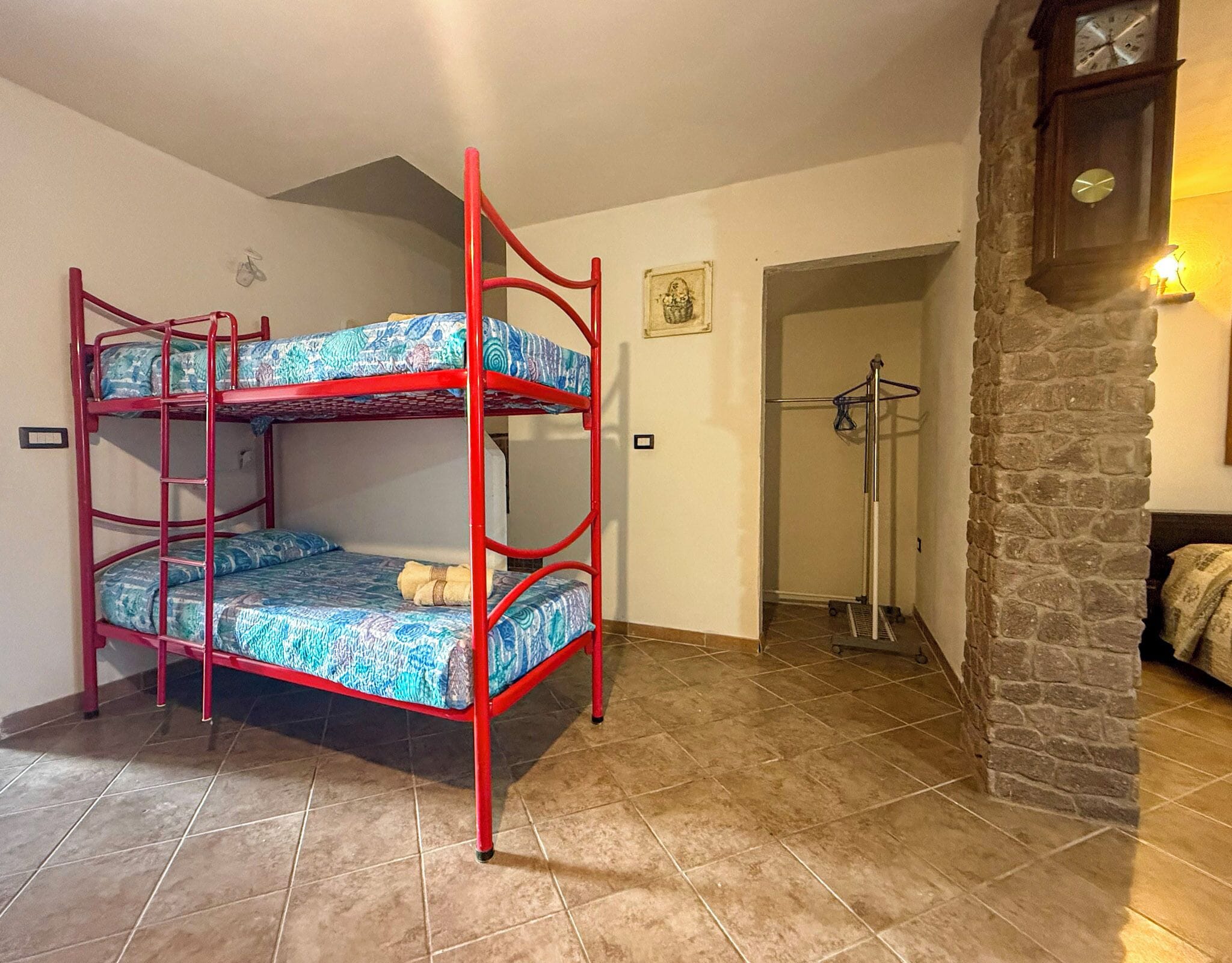 Dormitorio con literas, pared de piedra y un reloj.