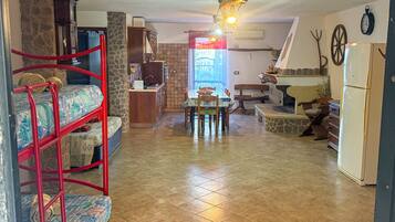 A compact living space with a bunk bed, kitchenette, dining area, and a stone fireplace.