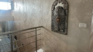 Una scala con ringhiera in metallo, un muro decorativo con motivi intricati e una piccola finestra.
