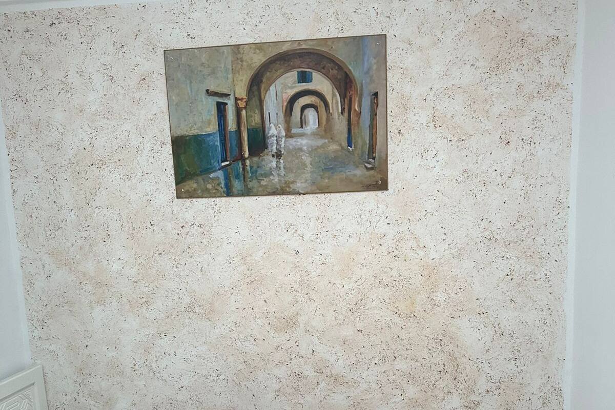 Une chambre à coucher avec un lit, un tableau au mur et un mur à texture.