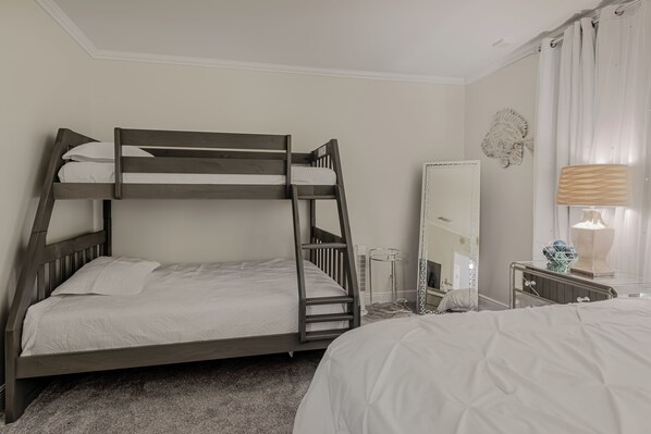 A bunk bed with a ladder, a bedside table with a lamp, and a mirror on the wall. - Luxury Penthouse at Regency Towers | 4 Bedrooms | Gulf Views (Panama City Beach)