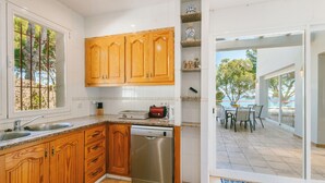 Een moderne keuken met houten kastjes, een vaatwasser en een eethoek met uitzicht.