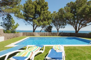 A swimming pool with lounge chairs, a stone wall, and trees. - Villa with pool and spectacular see views near the beach (Begur)