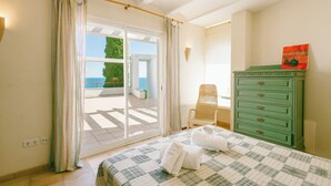 Een slaapkamer met een bed, een groene dressoir, een stoel en uitzicht op het groen.