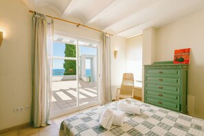 A bedroom with a bed, a green dresser, a chair, and a view of the outdoors. - Villa with pool and spectacular see views near the beach (Begur)