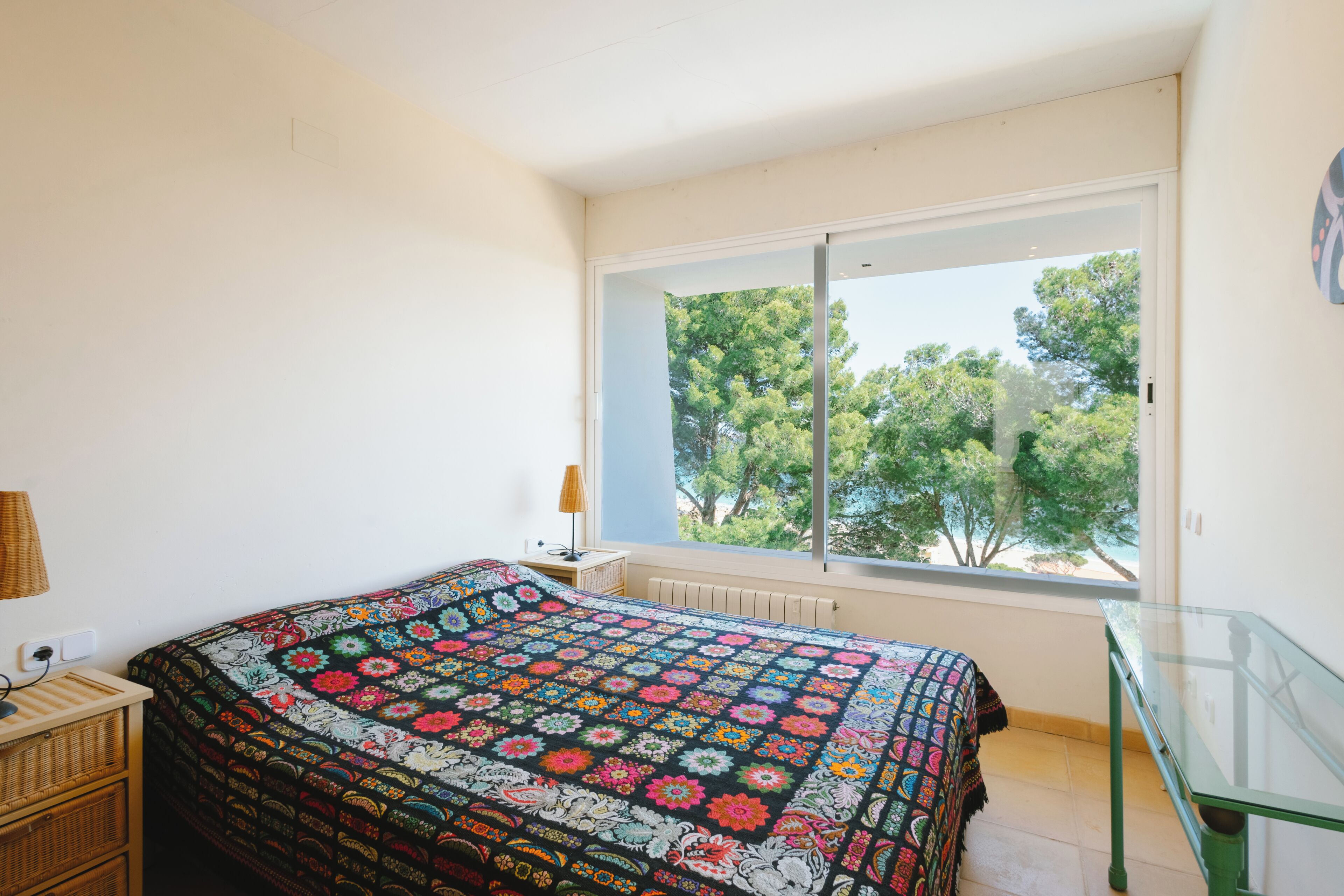 Una camera da letto con un letto, una finestra, un tavolino in vetro e una lampada.