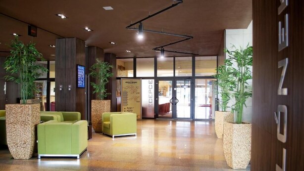 A hotel lobby with a reception desk, seating area, and large windows.