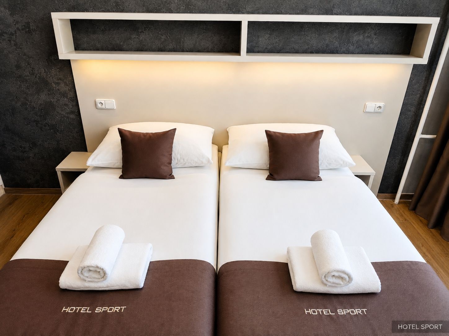 A double bed with two pillows, a nightstand, and a towel on each side.