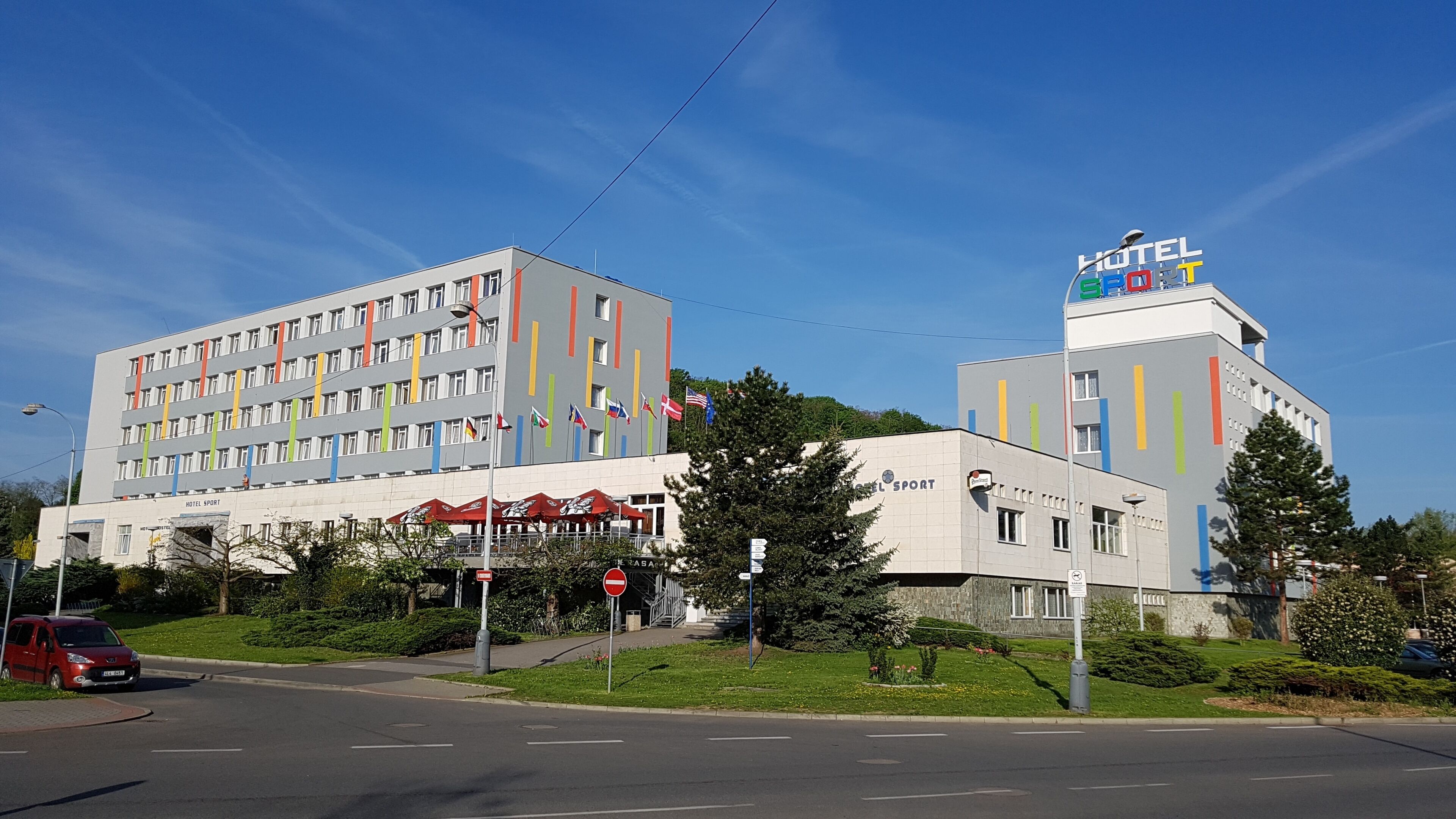 A hotel with multiple floors, a prominent 'HOTEL SPORT' sign, and a smaller building with a 'HOTEL' sign on top.