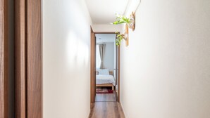 Un pasillo estrecho con piso de madera que conduce a un dormitorio con cama y una alfombra roja.