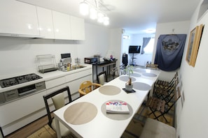 Una cocina moderna con armarios blancos, una estufa y un comedor con una mesa larga y sillas.
