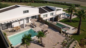 Uma casa moderna de dois andares com piscina, área de estar externa e vista para um rio.