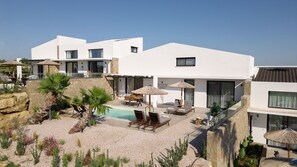 En modern villa med en swimmingpool, en uteplats och en stenmur.
