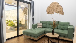 Uma sala de estar moderna com um sofá seccional verde, uma mesa de centro redonda e um objeto decorativo na parede.