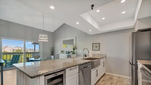 A modern kitchen with a large island, stainless steel appliances, and a view to the outside. - Sleep 8 next to the Beach! Balcony & Heated Pool (Indian Shores)