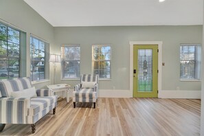 A room with a light-colored wooden floor, a green door with a glass panel, and striped upholstered furniture. - Downtown Oasis Home: Hot Tub, Pets OK, Sleeps 10 (Safety Harbor)