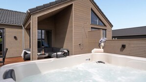 A modern house with a hot tub, a covered outdoor seating area, and a large window. - VillaVilla 541 - Bjerregård, Vestjylland (Hvide Sande)