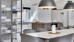 A modern dining area with a white table, grey chairs, and pendant lighting. - VillaVilla 541 - Bjerregård, Vestjylland (Hvide Sande)