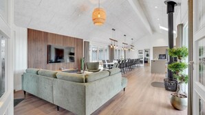Ein modernes Interieur mit einer Eckcouch, einem Flachbildfernseher und einem Essbereich mit Stühlen und Tisch.