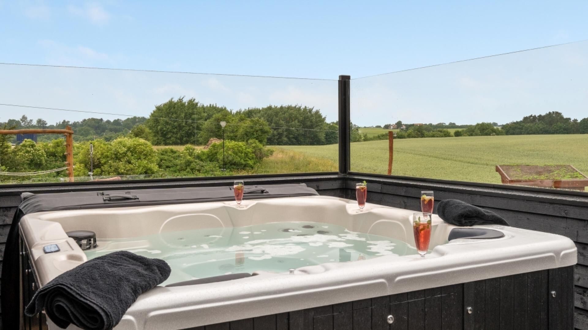 A hot tub with a view of a green field and trees.