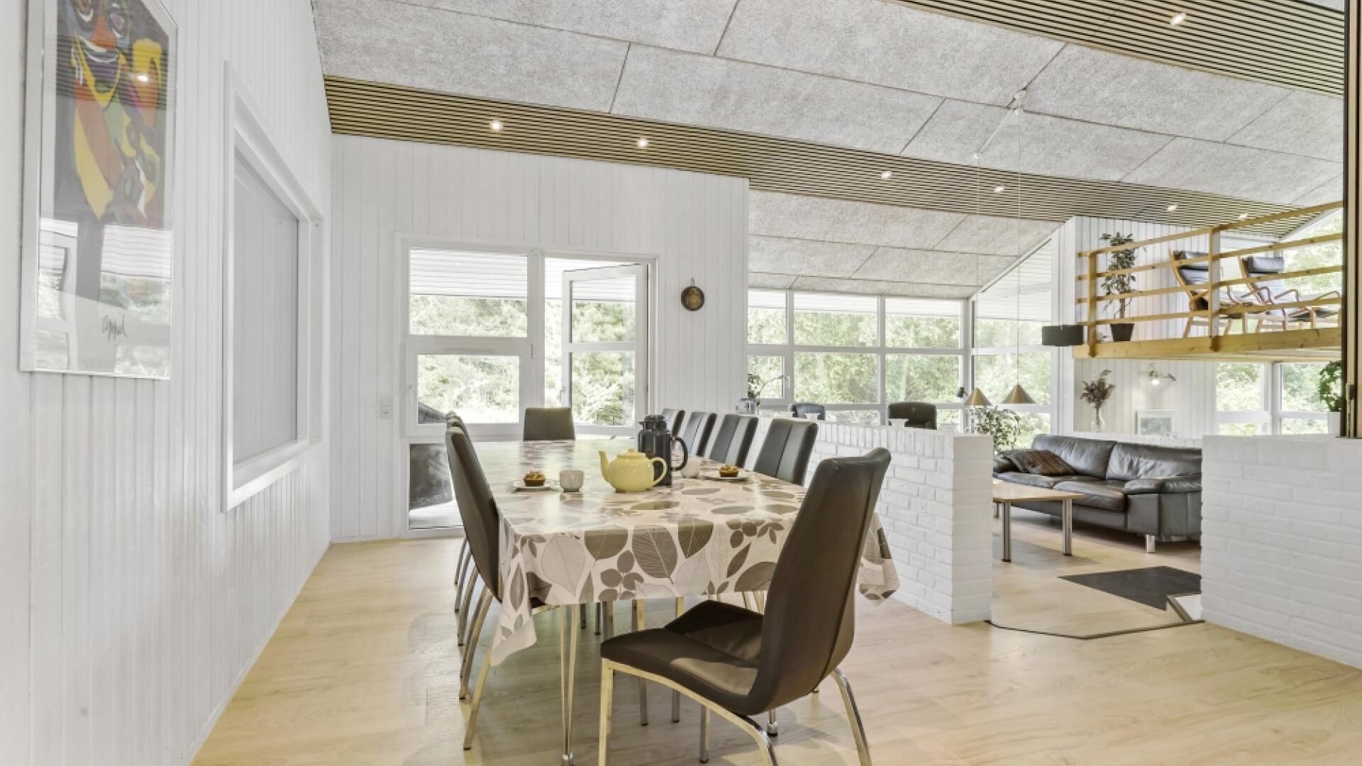 Et moderne spiseområde med et bord dækket til fire personer, omgivet af stole.